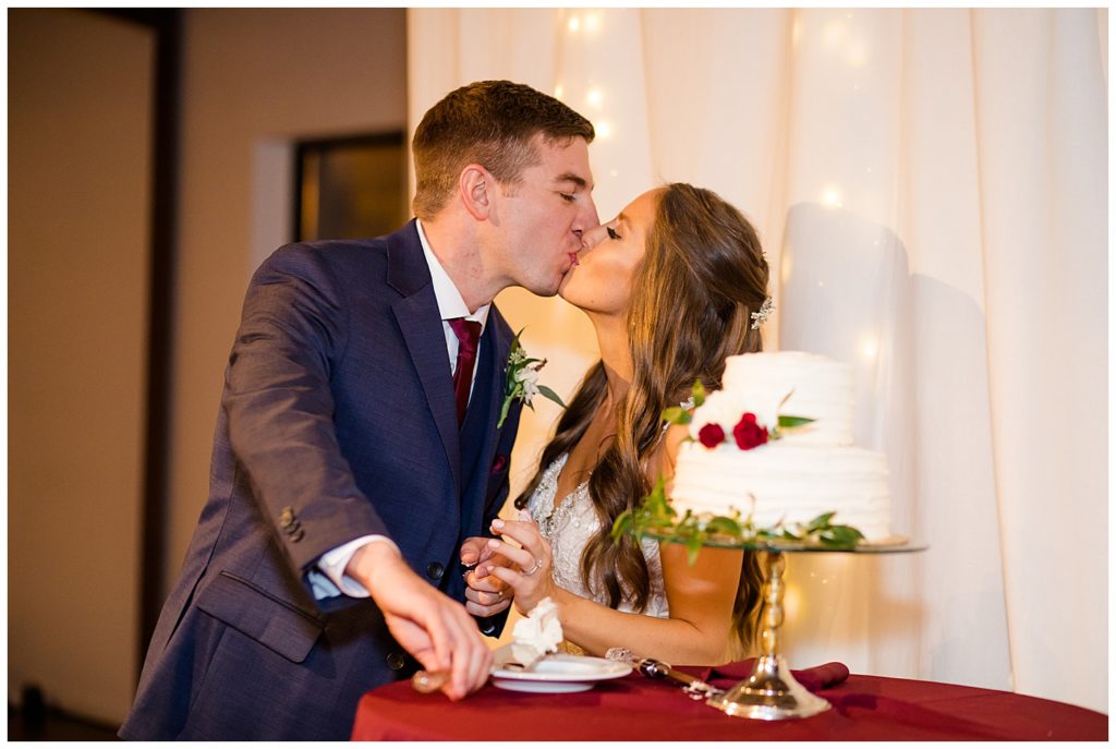 bride and groom share kiss after cutting cake at copius