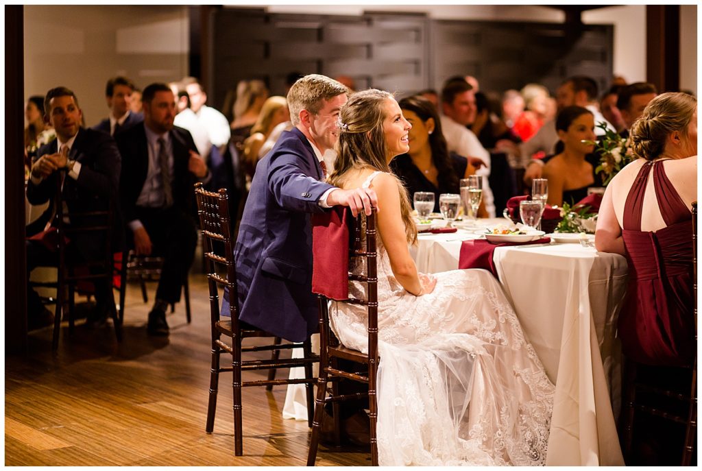 bride and groom laughing during father's speech at copius