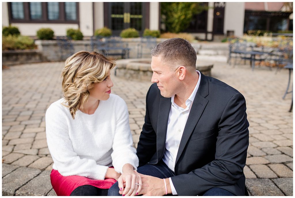 A picture of an engaged couple sitting, holding hands and thoughtfully gazing at each other in a quiet moment at Brookside Golf & Country Club by Columbus engagement photographer, Alayna Parker Photography