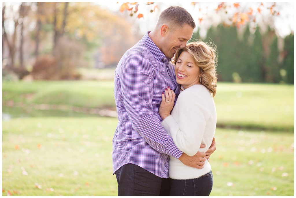 A photograph of a sweet moment as an engaged couple hold each other, smiling happily at Brookside Golf & Country Club by Columbus OH engagement photographer, Alayna Parker Photography