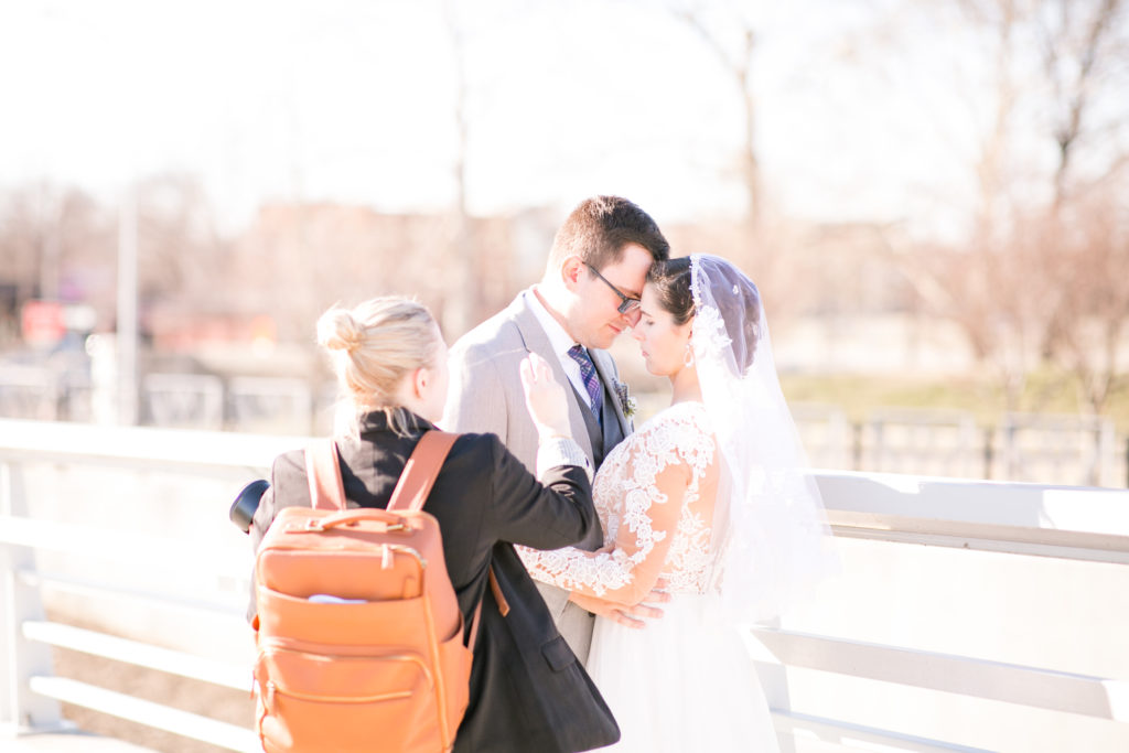photographer directing bride and groom to pose for photograph