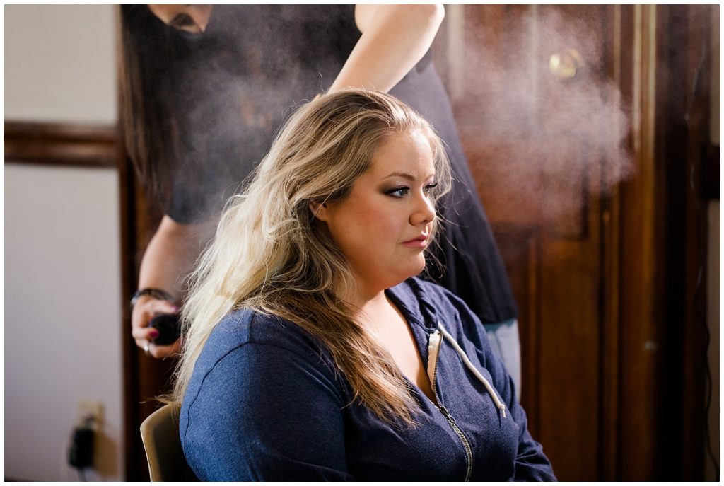 hair stylist hairsprays bride's hair at the postmark