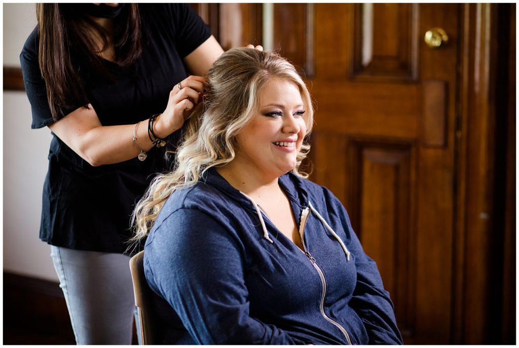 bride smiling while hair is being styled at the postmark
