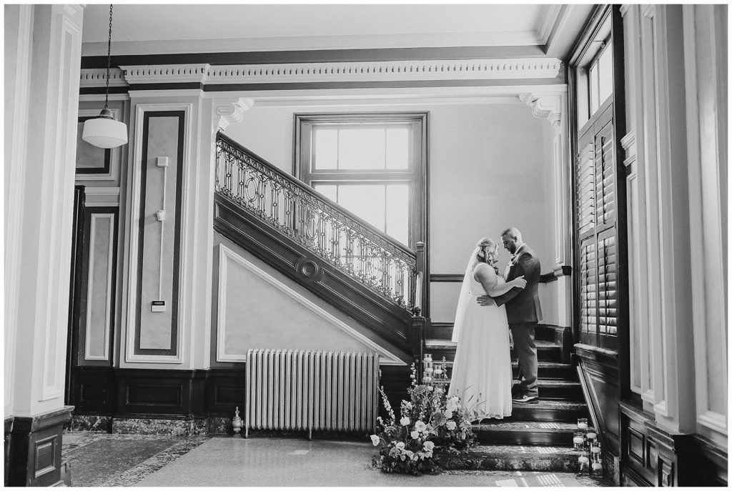 black and white image of bride and groom on staircase at the postmark
