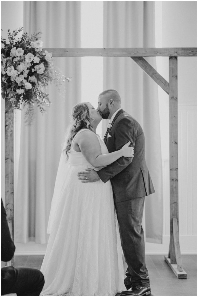black and white image of bride and groom's first kiss at the postmark