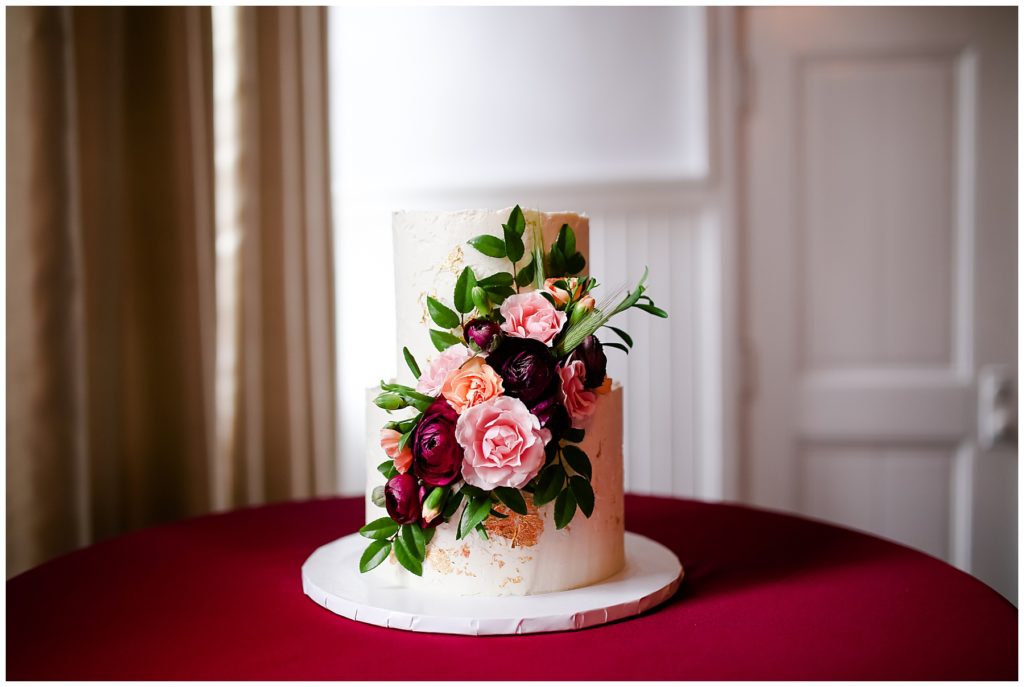 white wedding cake with pink and burgundy flowers at the postmark