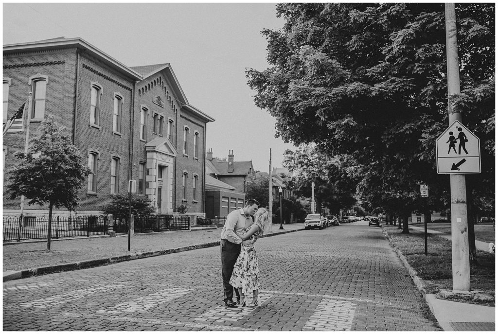 black and white image of engaged couple kissing in middle of brick street at schiller park